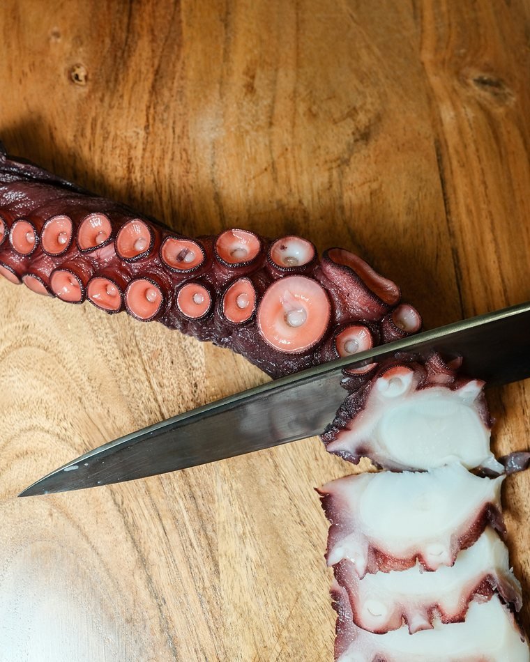 Tentáculo de pulpo cortado en láminas sobre tabla de madera